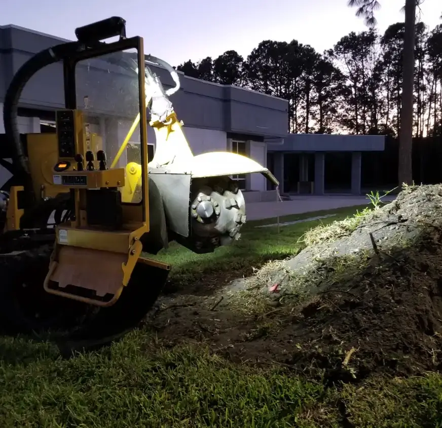 Vermeer stump grinder working a commercial Jacksonville property at dusk
